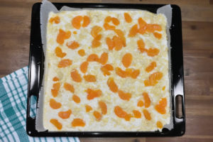 So sollte der Blechkuchen aussehen: Kokosflocken, Mandelblättchen und Mandarinen sind gleichmäßig (bis zum Rand) verteilt.