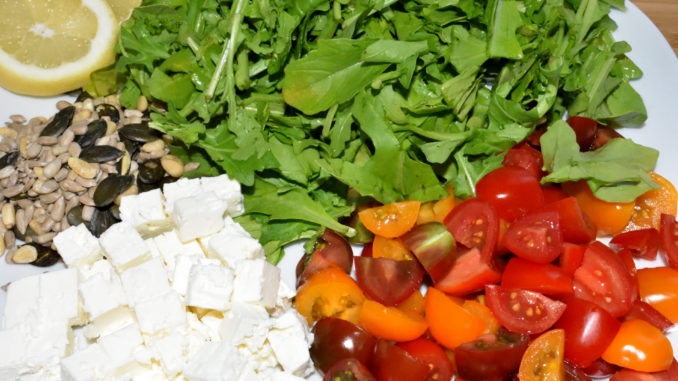 Lauter leckere Zutaten für meinen Salat: Rucola, Partytomaten, Fetakäse, Salat-Kernmischung und Zitrone.