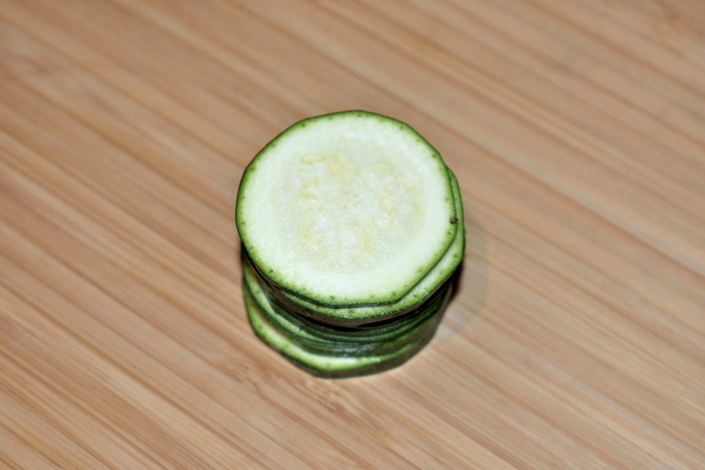 Zucchinis einfach würfeln - Schritt 1/3 | Als erstes schneidest Du die Zucchini in drei bis fünf Millimeter dicke Scheiben. Die Endstücke werden nicht gebraucht (darfst Du ganz allein aufessen).