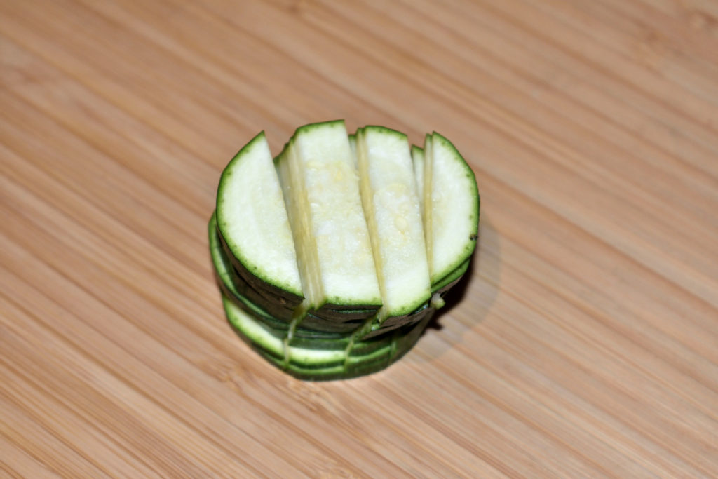 Zucchinis einfach würfeln - Schritt 2/3 | Jetzt kommt mein Geheimtrick: Nimm Dir jeweils eine Handvoll Zucchinischeiben, bau ein Türmchen und schneide es in Streifen.