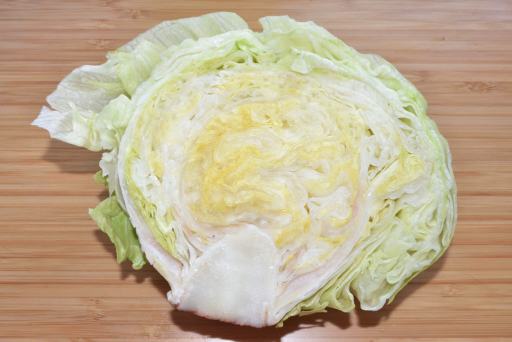 Eisbergsalat - so entfernst Du den Strunk 1/3 | Als erstes teilst Du den Salatkopf mit einem langen, scharfen Messer in zwei Hälften.